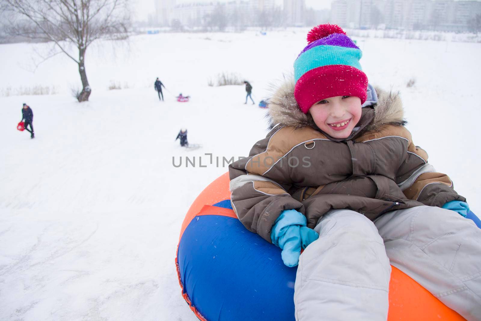 Sledding.Happy child on vacation. Winter fun and games.Little boy enjoying a sleigh ride.Children play outdoors in snow. Kids sled in the Alps mountains in winter
