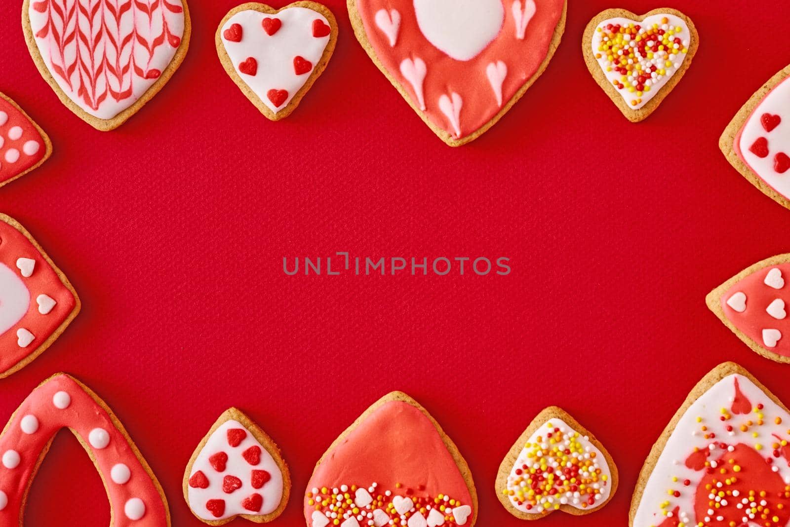 Frame with glazed and decorating heart shape cookies on red background. Valentines Day food concept