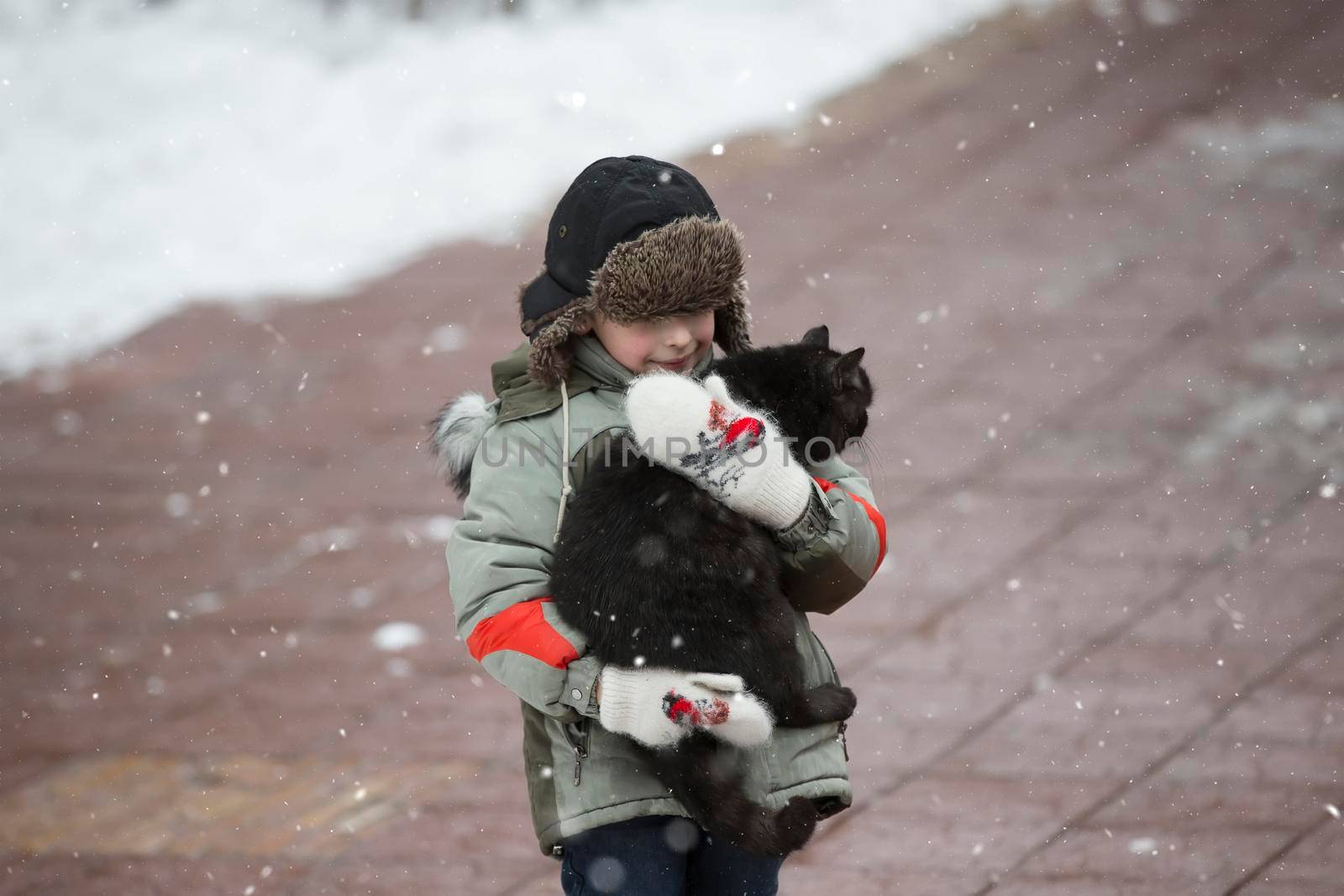 A boy in a hat with a fur hat with a homeless cat
