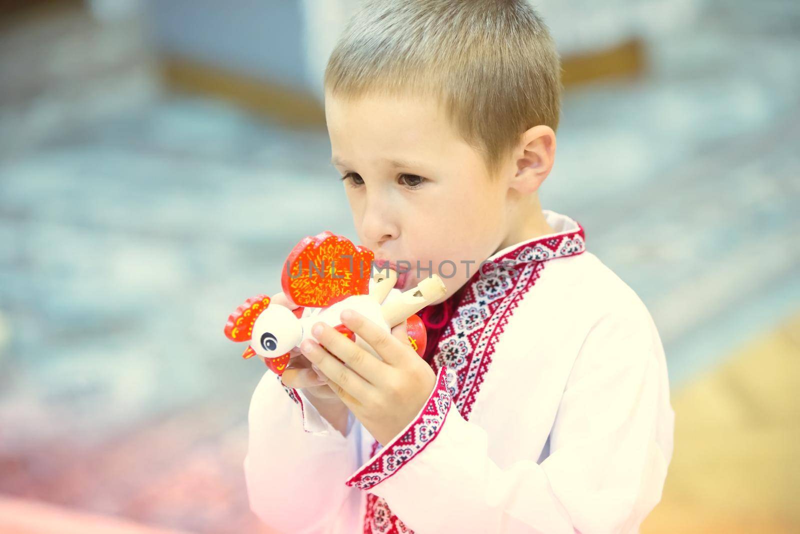 The boy in national clothes blows into the whistle. The Belarusian boy. The boy blows into the whistle