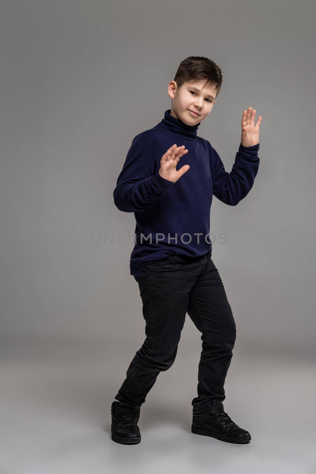 Nice schoolboy is posing at studio over a gray background. by nazarovsergey