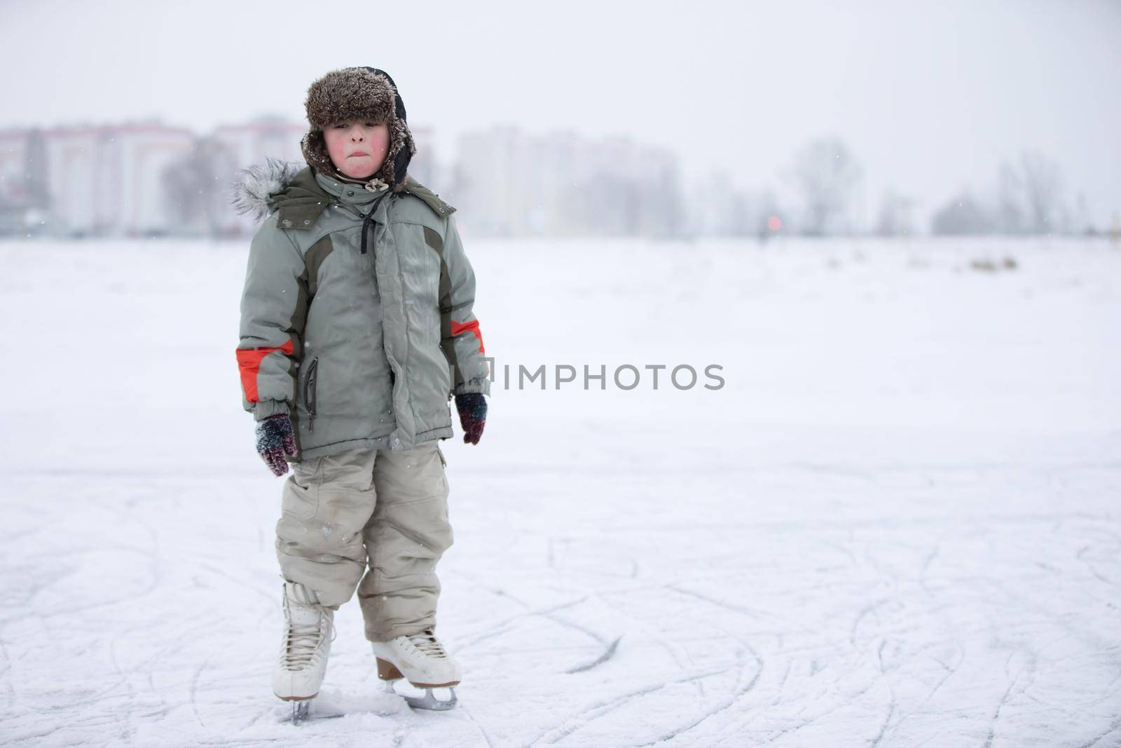 A child is a boy on skates on a snowy lake. Learn to ride