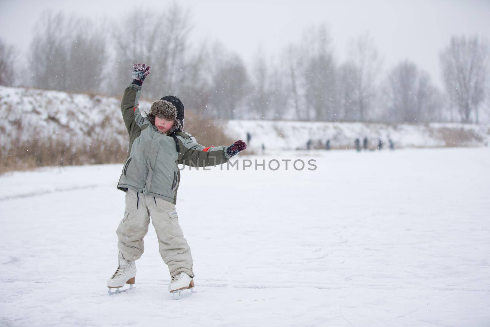 The kid learn to skate. The boy on the lake in winter snowy day on skates. Skating on the lake