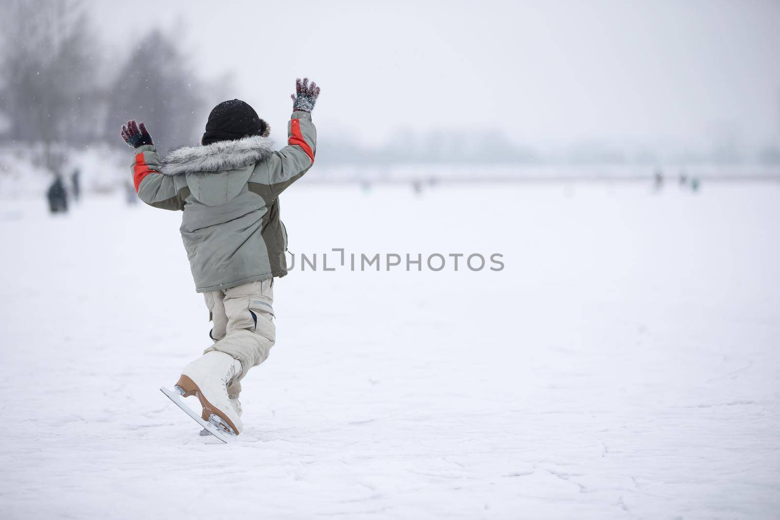 A little boy in huge skates is riding on the lake
