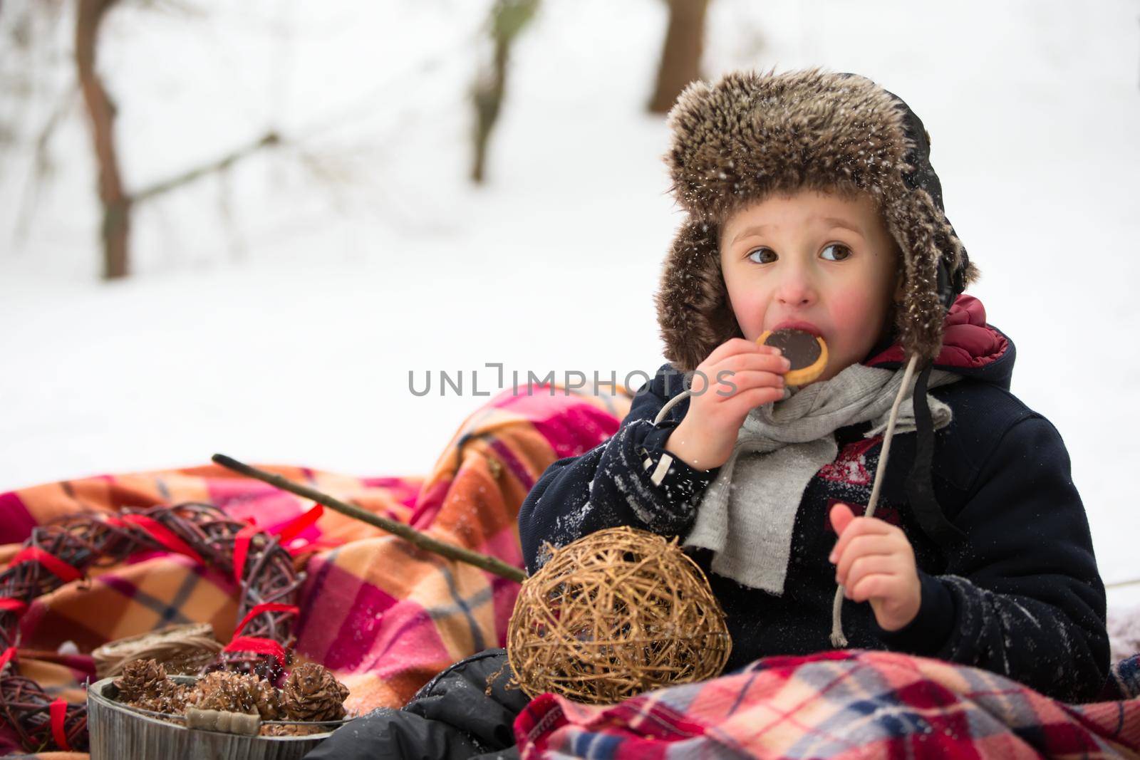 A little boy on a winter picnic eating chocolate biscuits