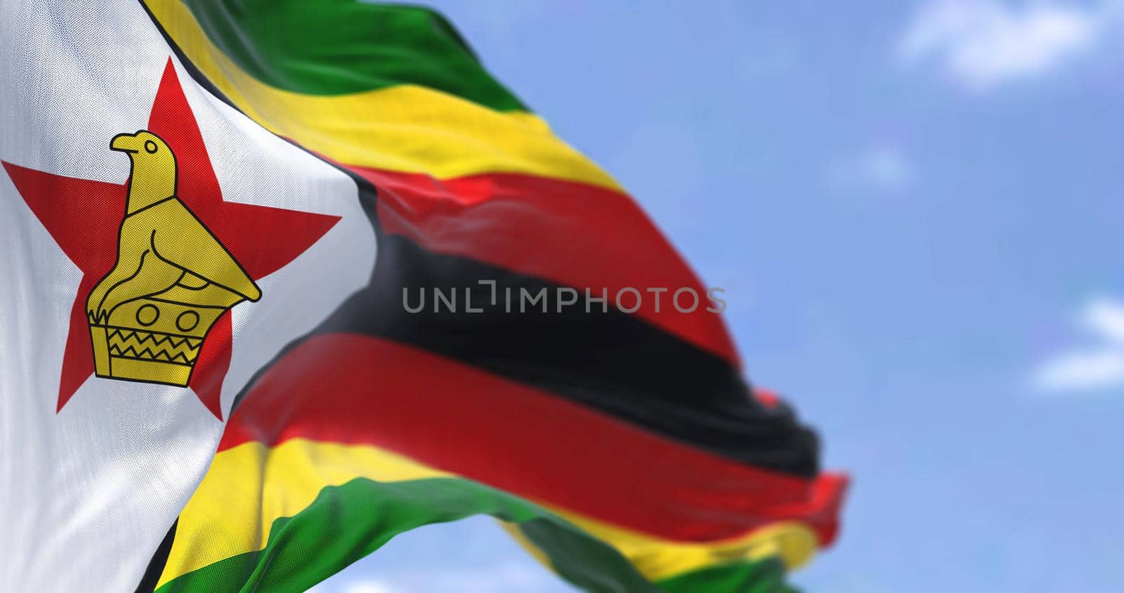 Detail of the national flag of Zimbabwe waving in the wind on a clear day. by rarrarorro