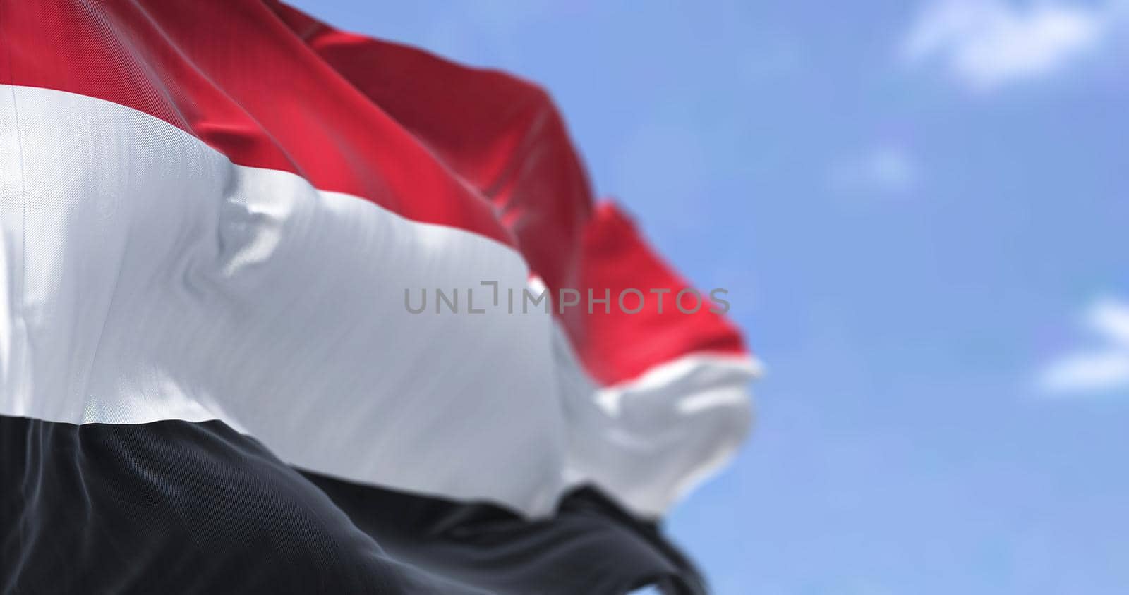 Detail of the national flag of Yemen waving in the wind on a clear day by rarrarorro