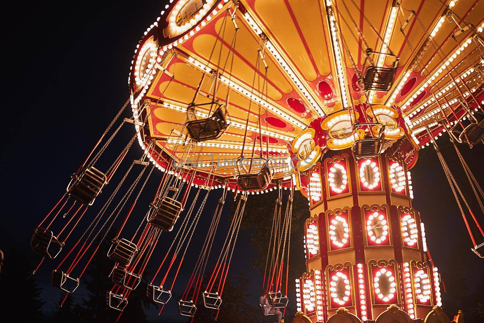 Illuminated swing chain carousel in amusement park at night