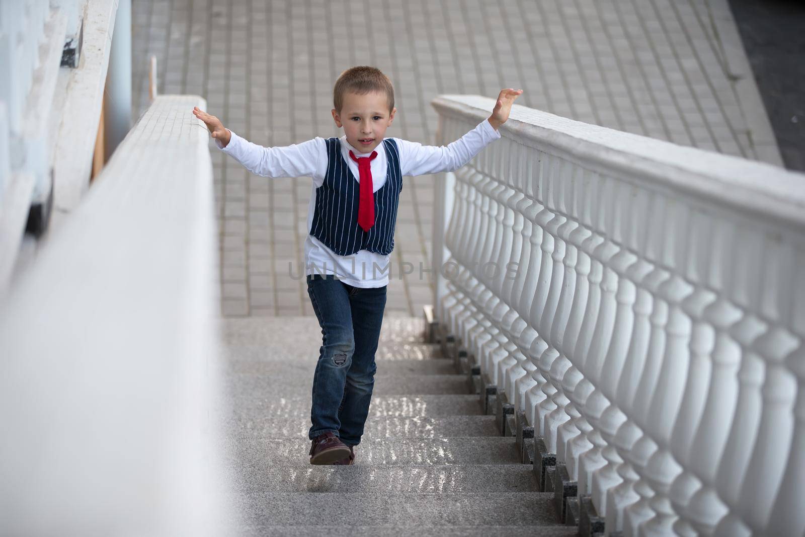 A child in a tie climbs up the stairs