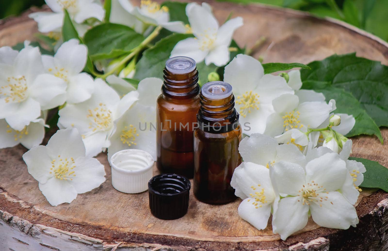 Essential oil and jasmine flowers on a wooden background. Cosmetic procedures. Selective focus