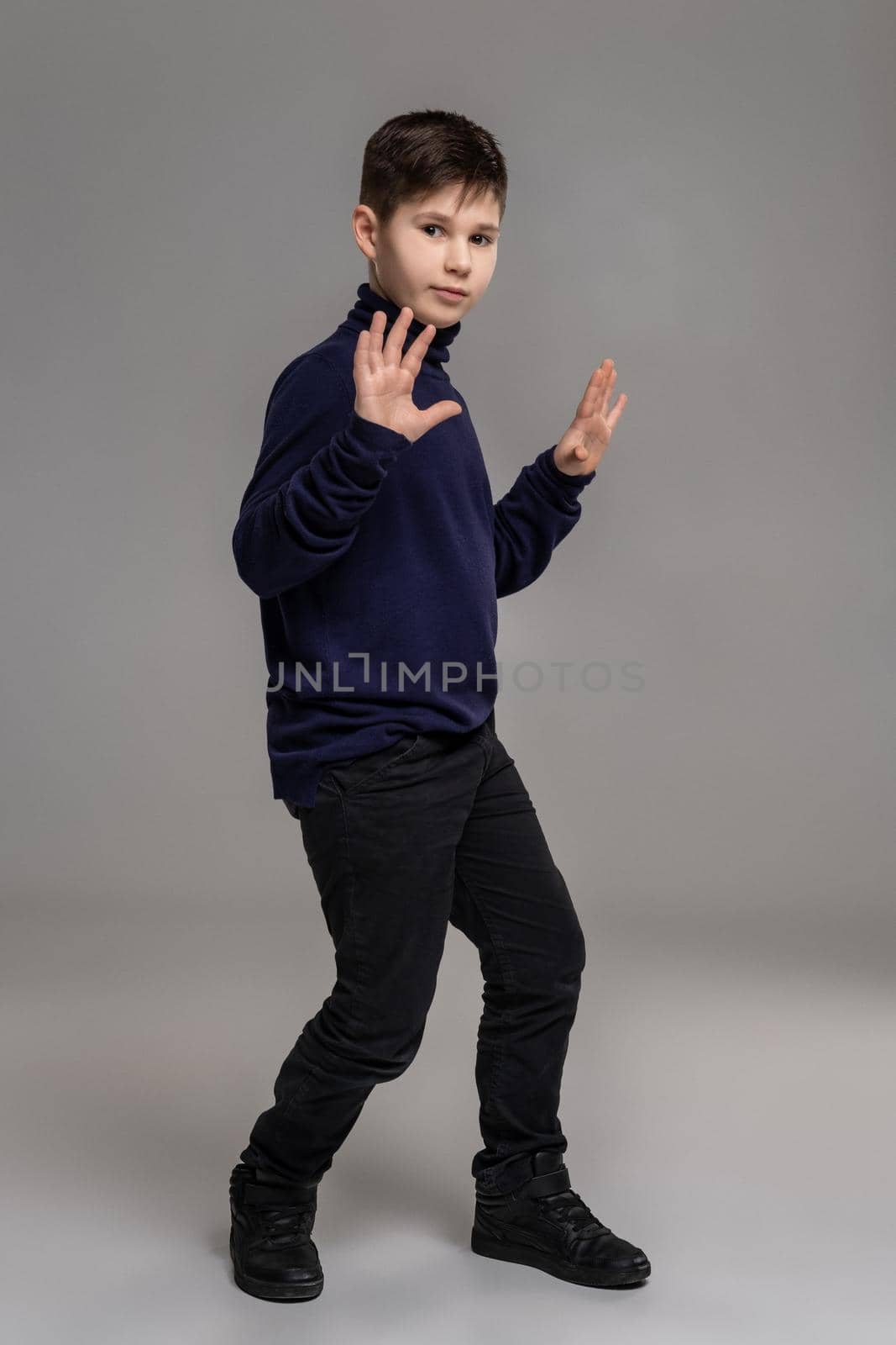 Nice schoolboy is posing at studio over a gray background. by nazarovsergey