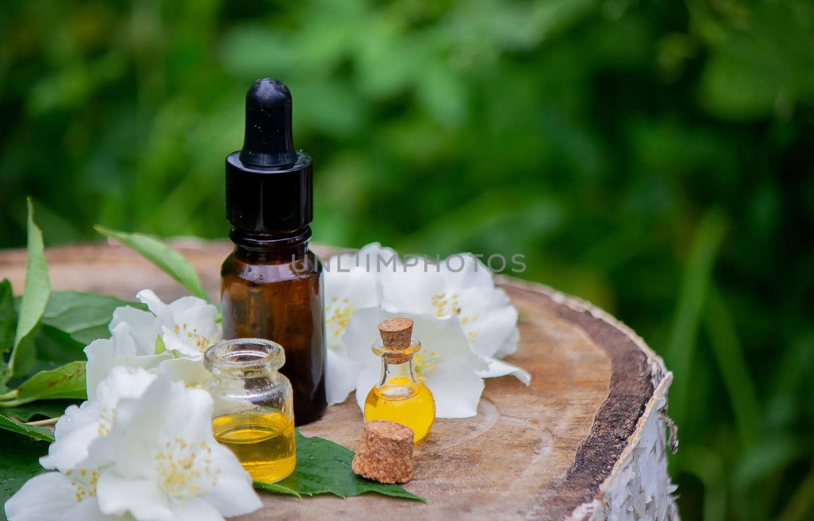 Essential oil and jasmine flowers on a wooden background. Cosmetic procedures. Selective focus