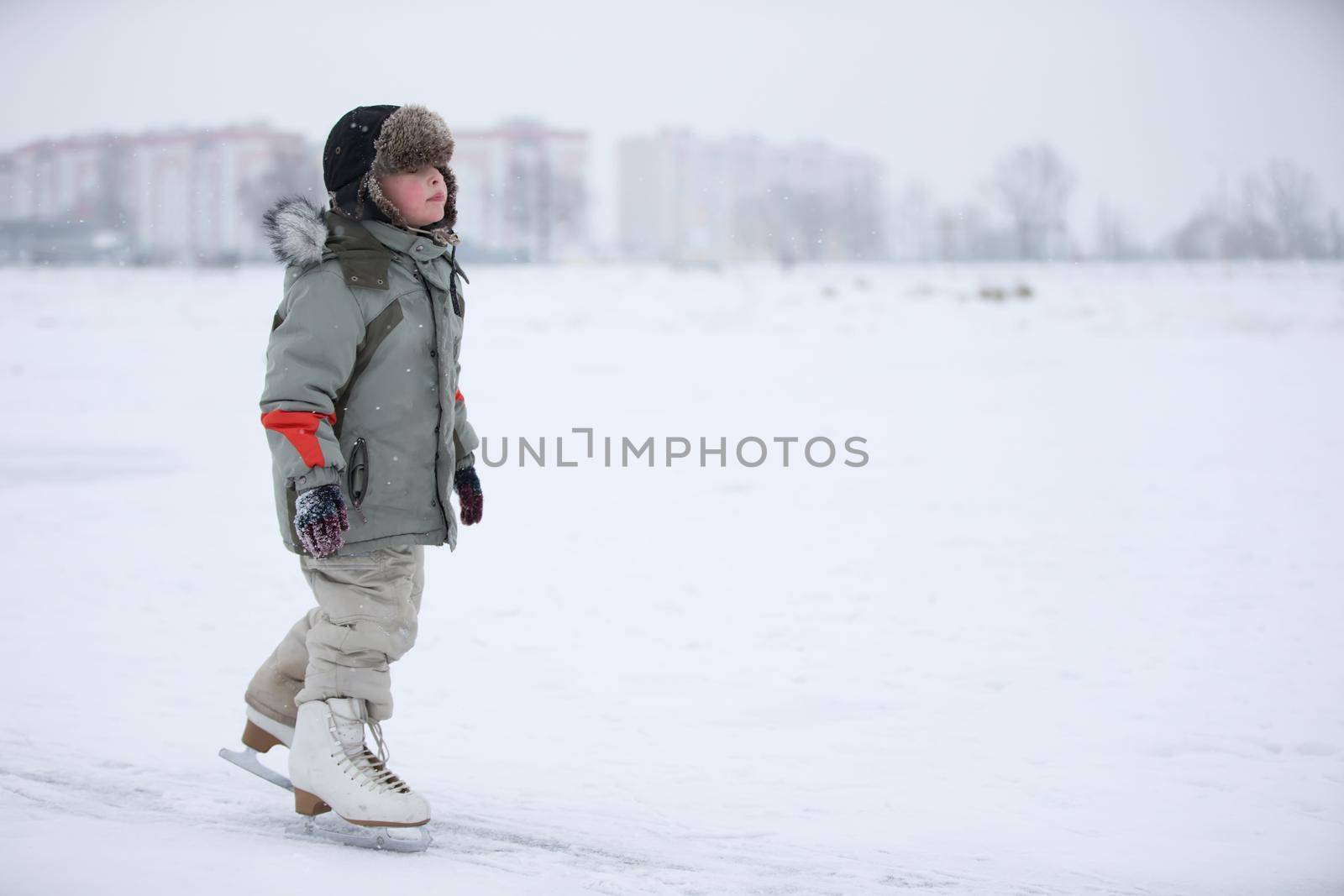 Ice skating boy on the lake.The boy is skating on the lake. Little baby in huge skates