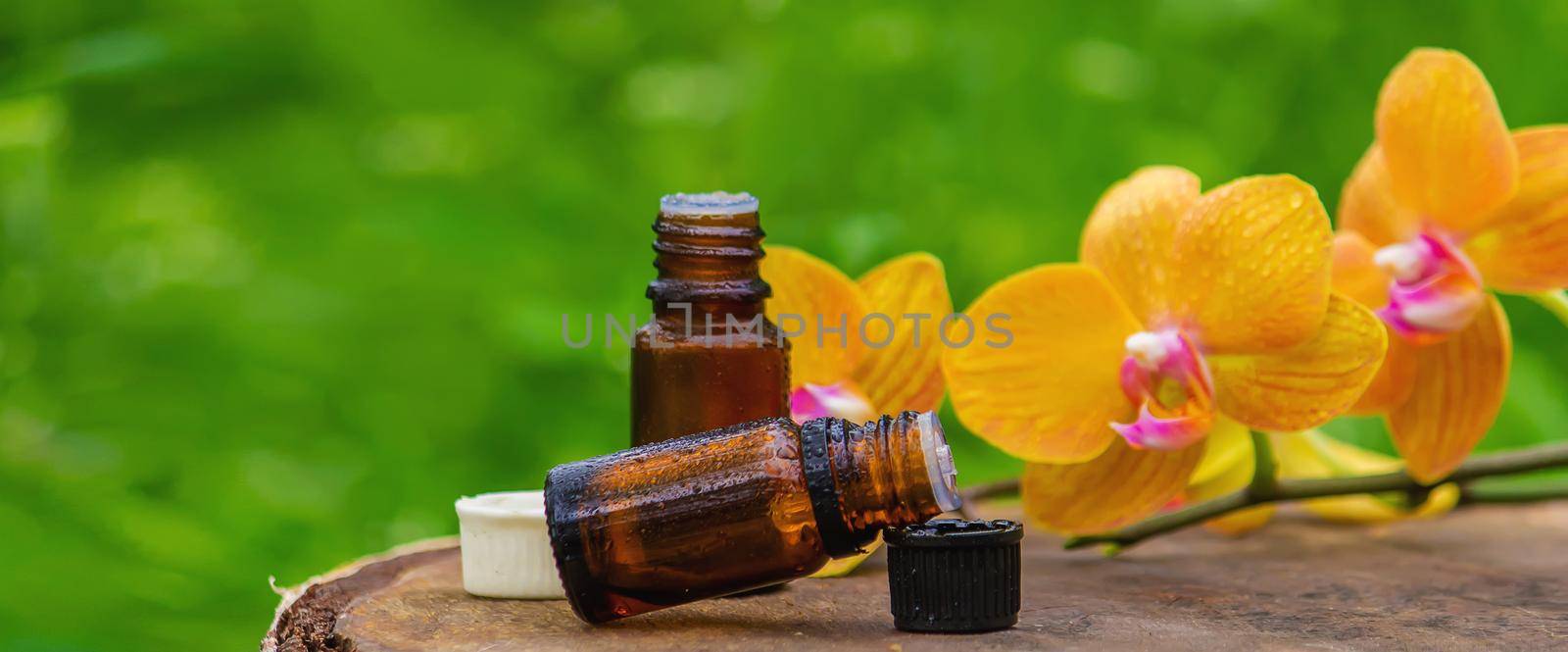 Massage oil and stones with yellow orchid. Natural oils. Selective focus.