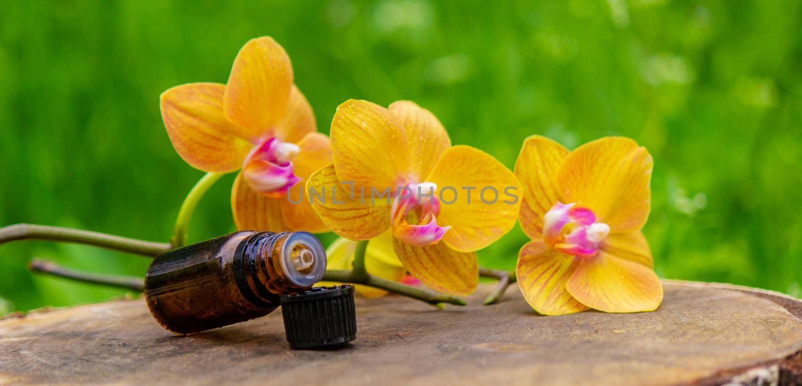 Massage oil and stones with yellow orchid. Natural oils. Selective focus.
