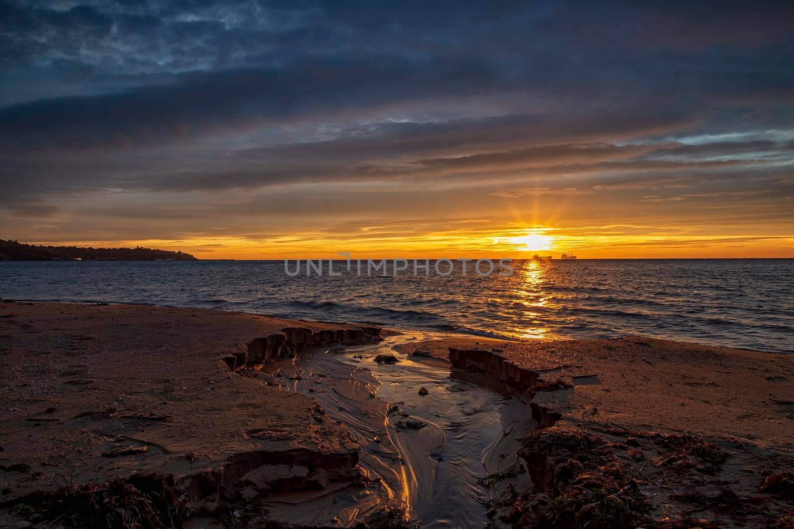 Sea sunrise with a small brook flowing into the sea 