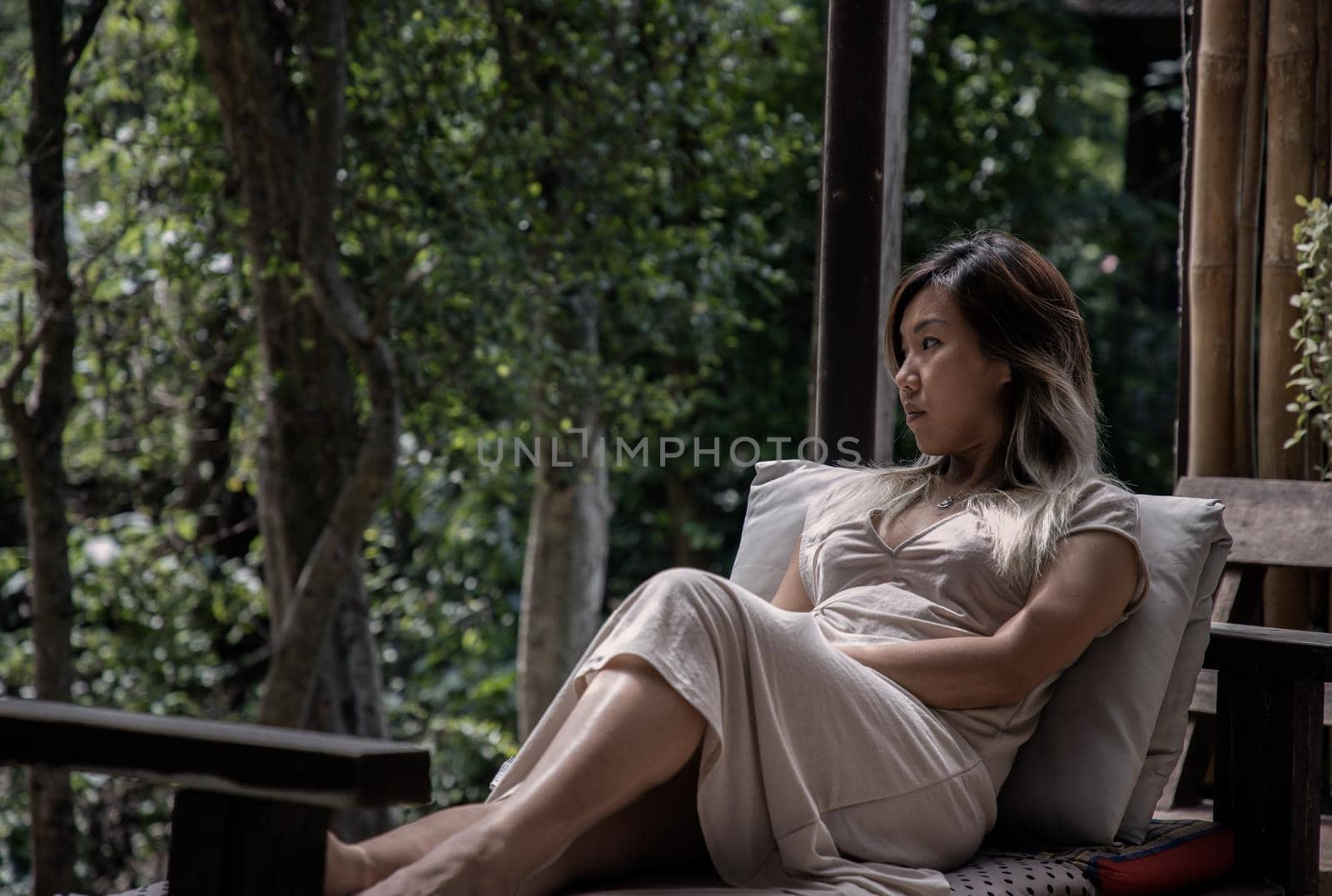 Young woman enjoys the nature while sits on cozy wooden balcony of a wooden country house. Concept of solitude and recreation on nature. Selective focus.