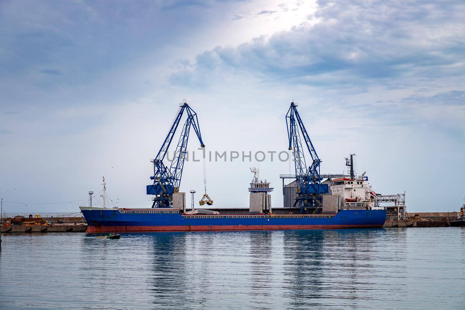 trading ship of the port city ready for loading materials with the cranes. by EdVal