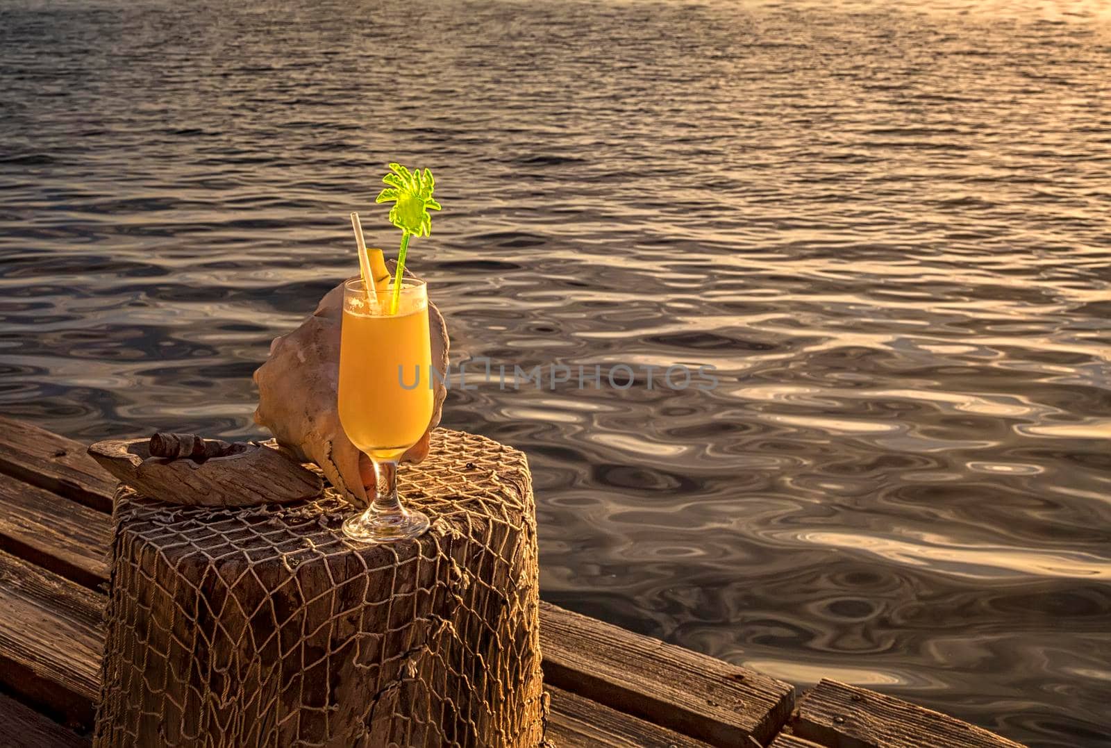 Cocktail with a straw on a wooden handmade table. Cocktail on vacation on a tropical island.