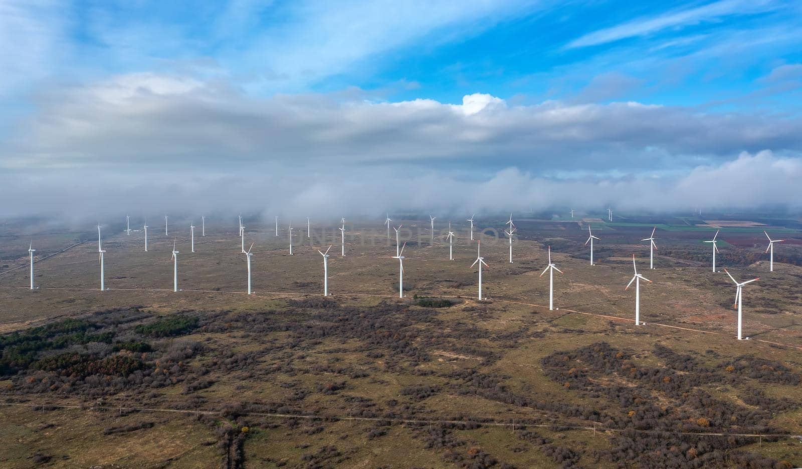 Aerial view to big wind turbine farm. Horizontal view with cloudy sky. by EdVal