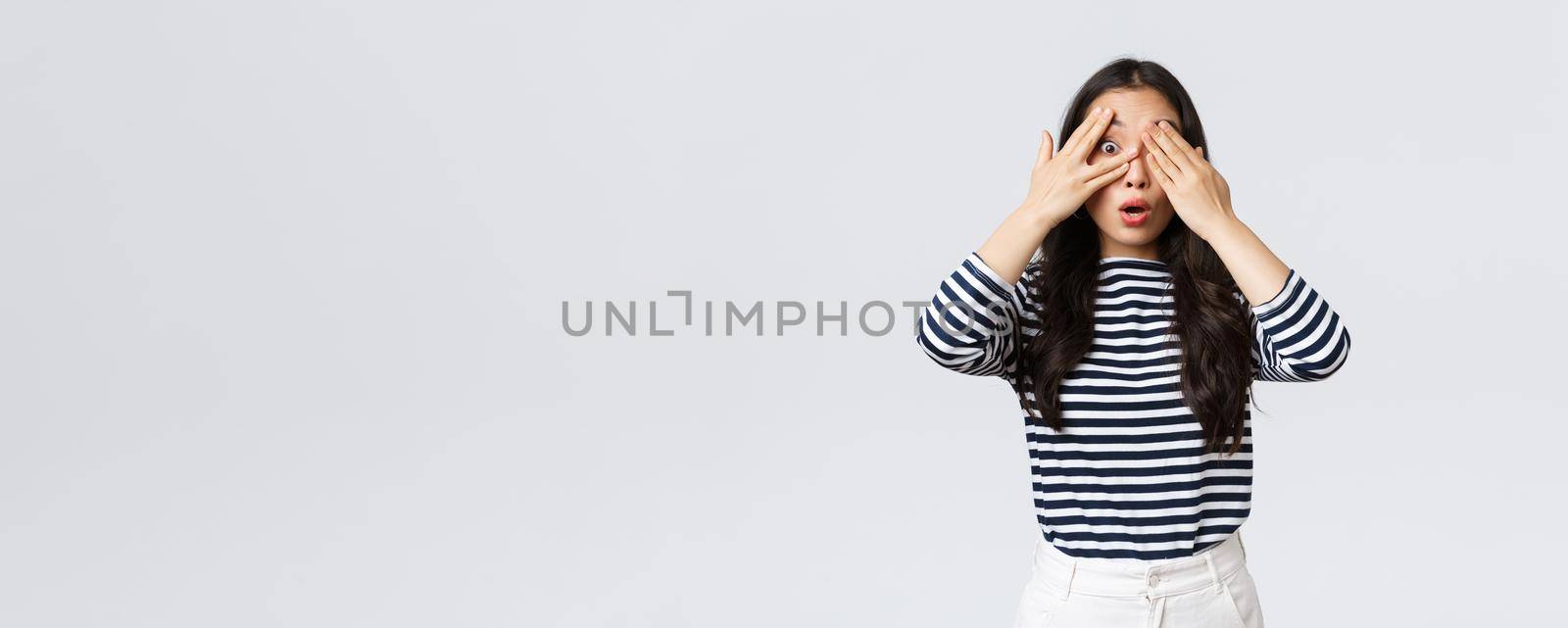 Lifestyle, beauty and fashion, people emotions concept. Dreamy gorgeous asian girl anticipating surprise. Asian woman close eyes and peeking through fingers curious what happening.