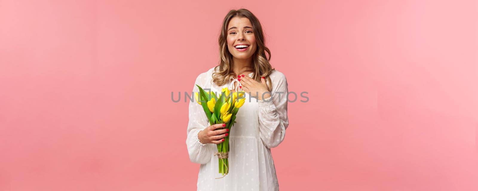 Holidays, beauty and spring concept. Grateful charming blond girl receive yellow tulips, feel touched thanking for romantic gift, sighing lovely smiling, feel happy hold flowers, pink background by Benzoix