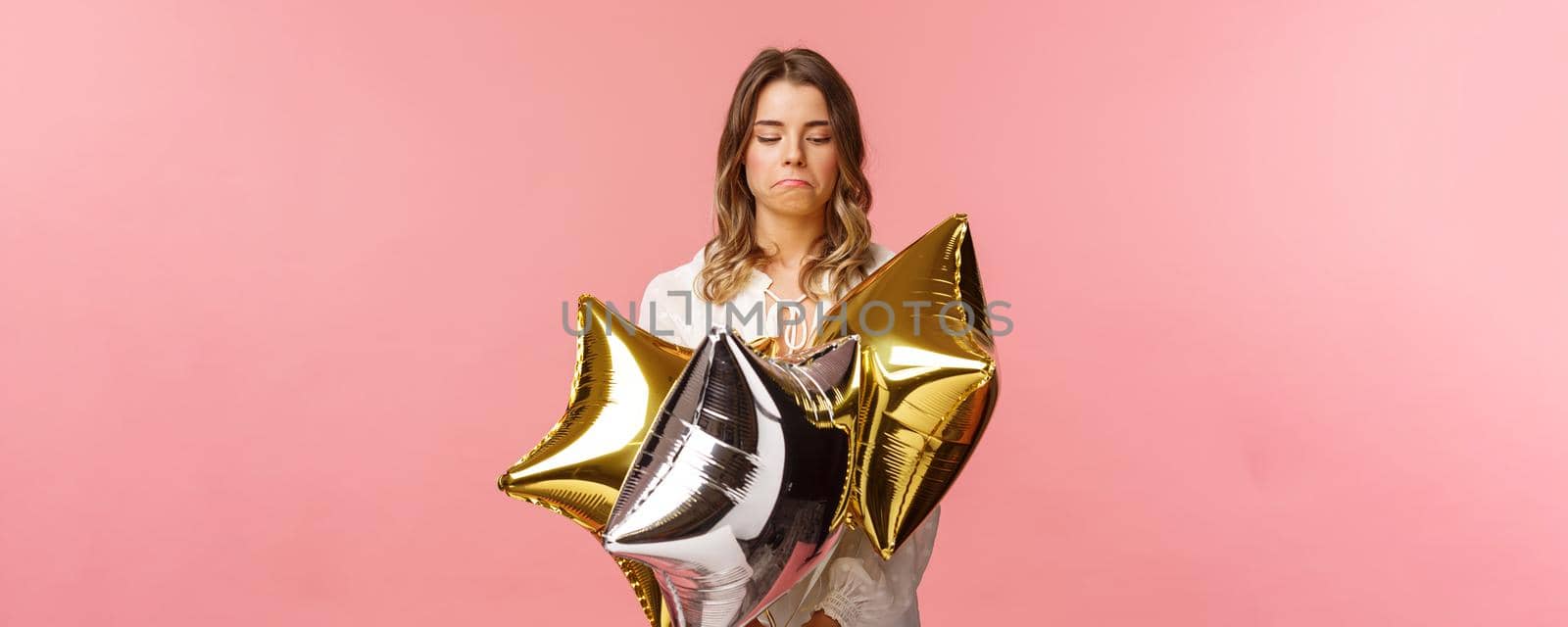 Holidays, celebration and women concept. Portrait of satisfied good-looking blond girl make not bad face, pulling lips down and nod in approval, looking at cool star-shaped balloons.