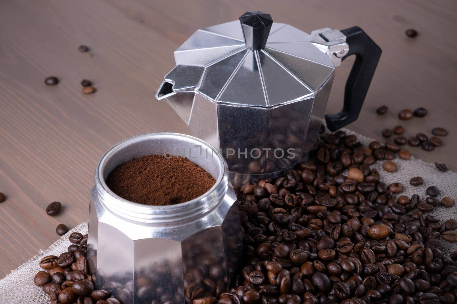 Close-up of disassembled geyser coffee maker on wooden surface. Coffee beans in pile, ground and brewed coffee. Coffee preparation. Selective focus.