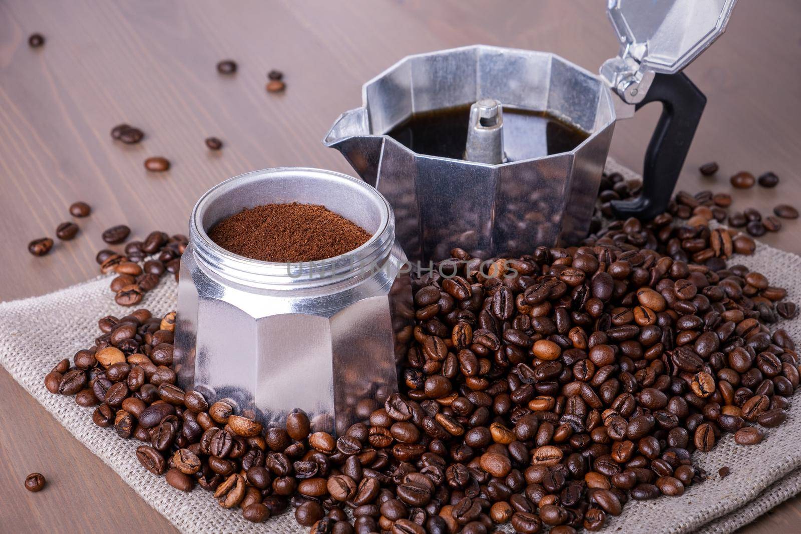 Close-up of disassembled geyser coffee maker on wooden surface. Coffee beans in pile, ground and brewed coffee. Coffee preparation. Selective focus.