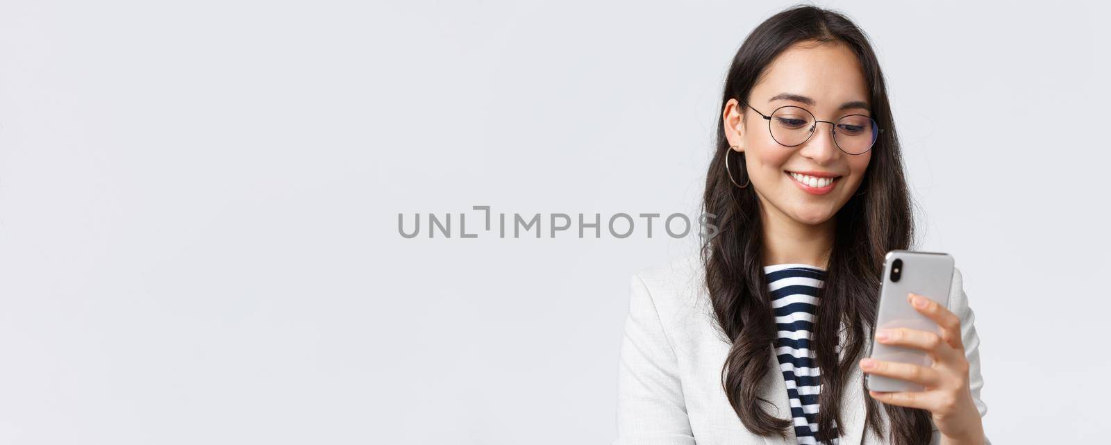 Business, finance and employment, female successful entrepreneurs concept. Close-up of stylish modern businesswoman in suit and glasses messaging, using mobile phone.