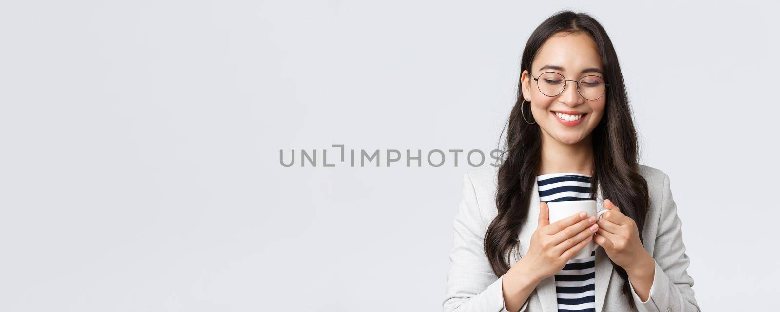 Business, finance and employment, female successful entrepreneurs concept. Smiling happy asian businesswoman having coffee break, hugging her favorite mug at office.