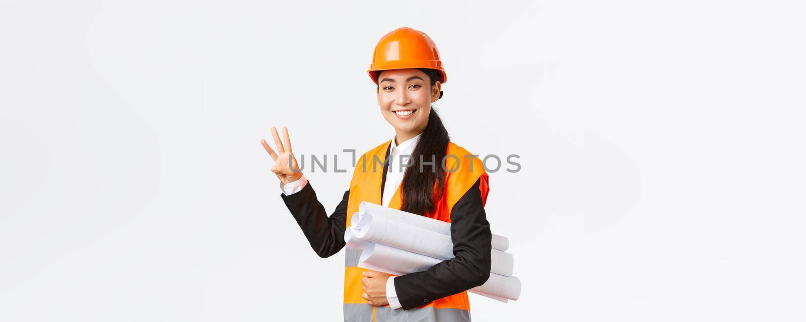 Smiling asian female architect at construction area, building estates, showing number three, carry blueprint as wearing safety helmet, giving fixed time for task done, white background.