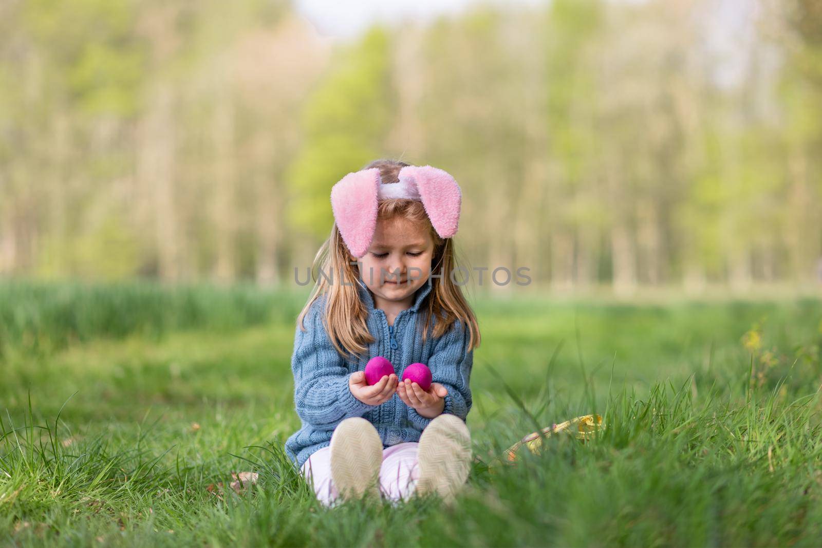 Girl with bunny ears collects the eggs in a basket for Easter