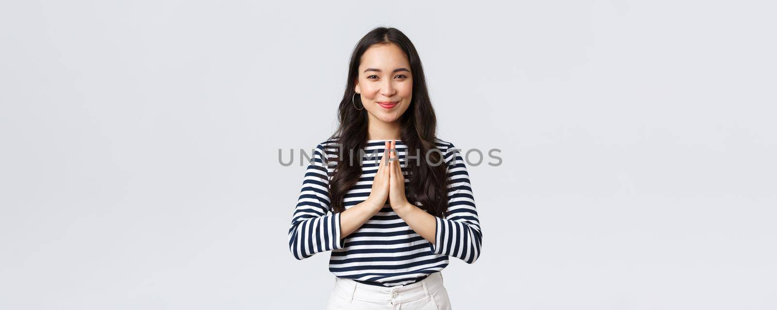 Lifestyle, people emotions and casual concept. Cute asian girl in casual outfit smiling as saying namaste, holding hands in pray, pleading or greeting guests with polite bow by Benzoix