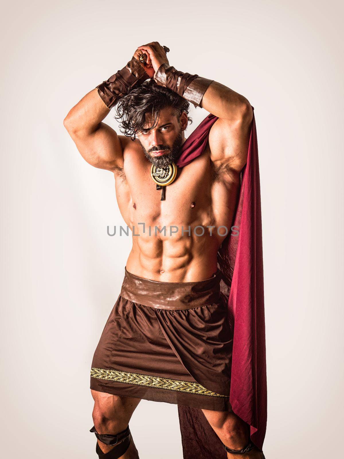 Handsome muscular man posing in roman or spartan gladiator costume with shield and sword, isolated on black background in studio