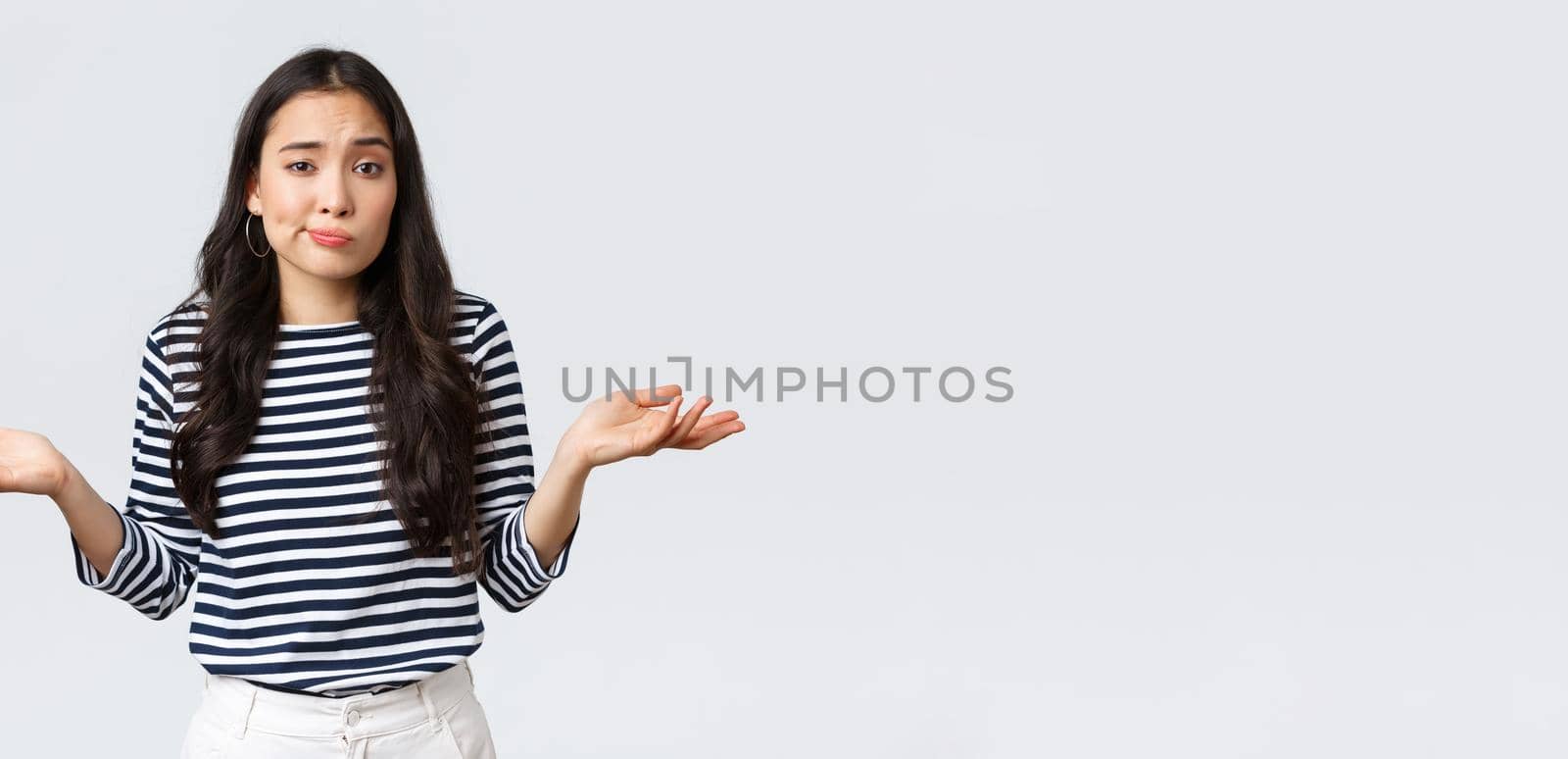 Lifestyle, beauty and fashion, people emotions concept. Smiling cute clueless girl dont have idea, no answer, shrugging with hands spread sideways, standing white background by Benzoix