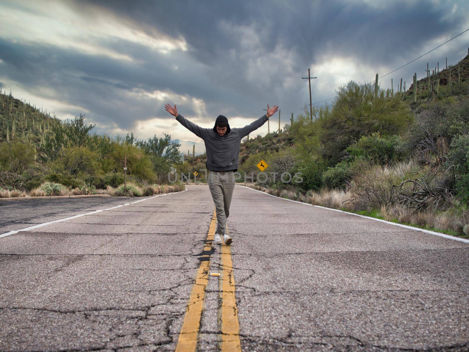 Attractive young man walking or standing in the middle of country road, with open arms