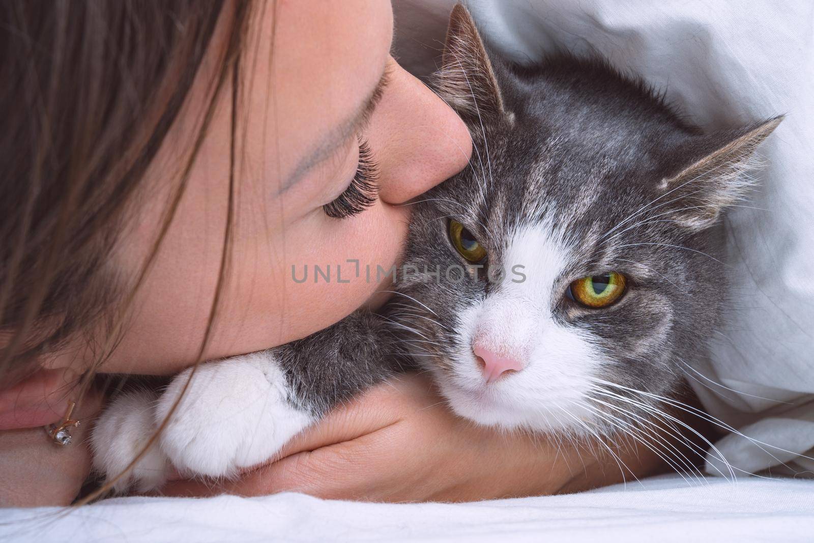 Beautiful woman kissing funny grumpy cat. People and pets love and friendship. Cat and owner together. Cat lover. High quality photo