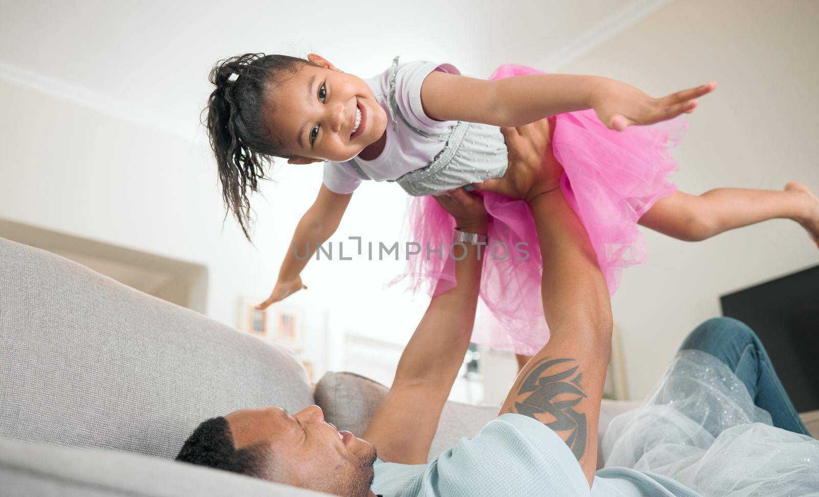 Look, Im a plane. Shot of an adorable little girl bonding with her father in the living room at home. by YuriArcurs