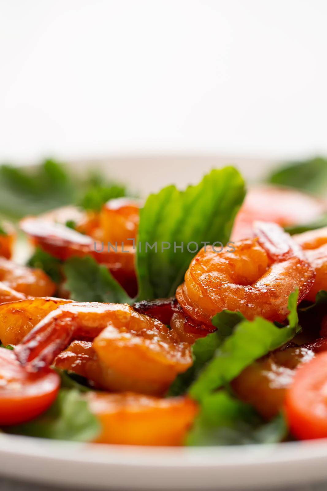 Close-up of fresh shrimp, tomato, arugula and greens salad, vertical image with copy space by galsand