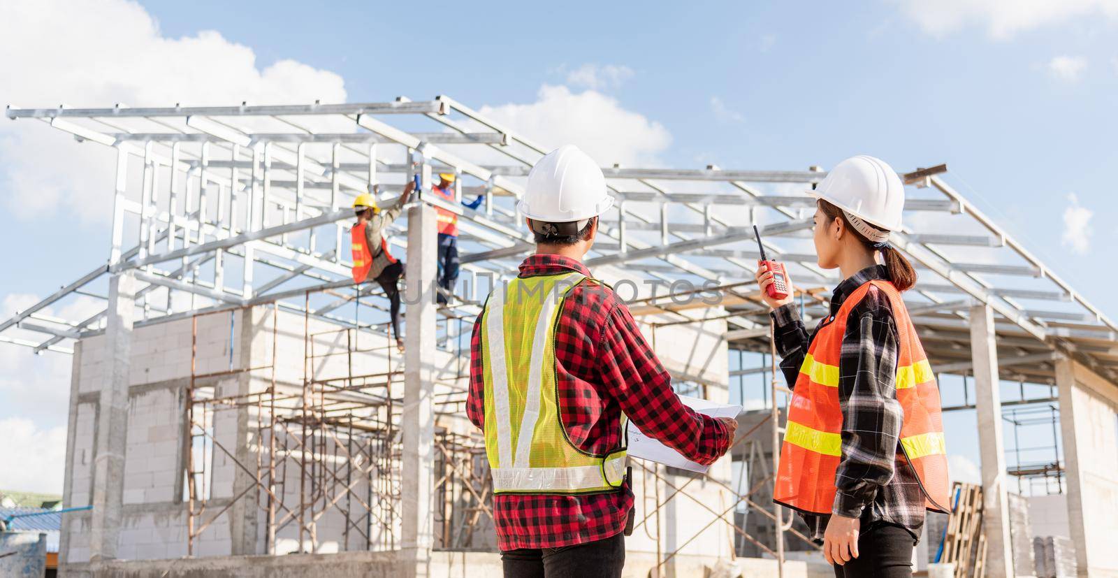 Back two architect and client discussing help create plan with blueprint home building at construction site. Asian engineer foreman worker man and woman meeting talking on drawing paper project