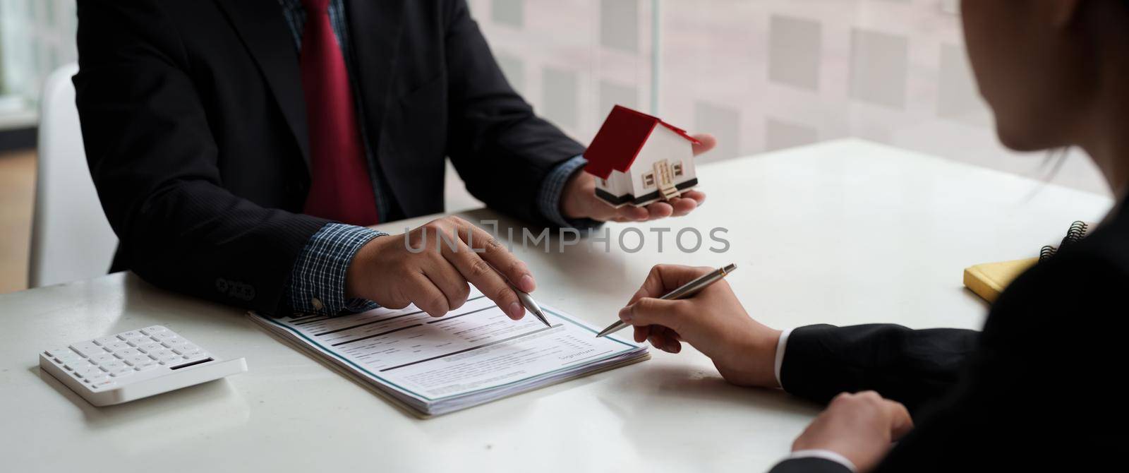 Businessman and estate agent signing a document for house deal by nateemee