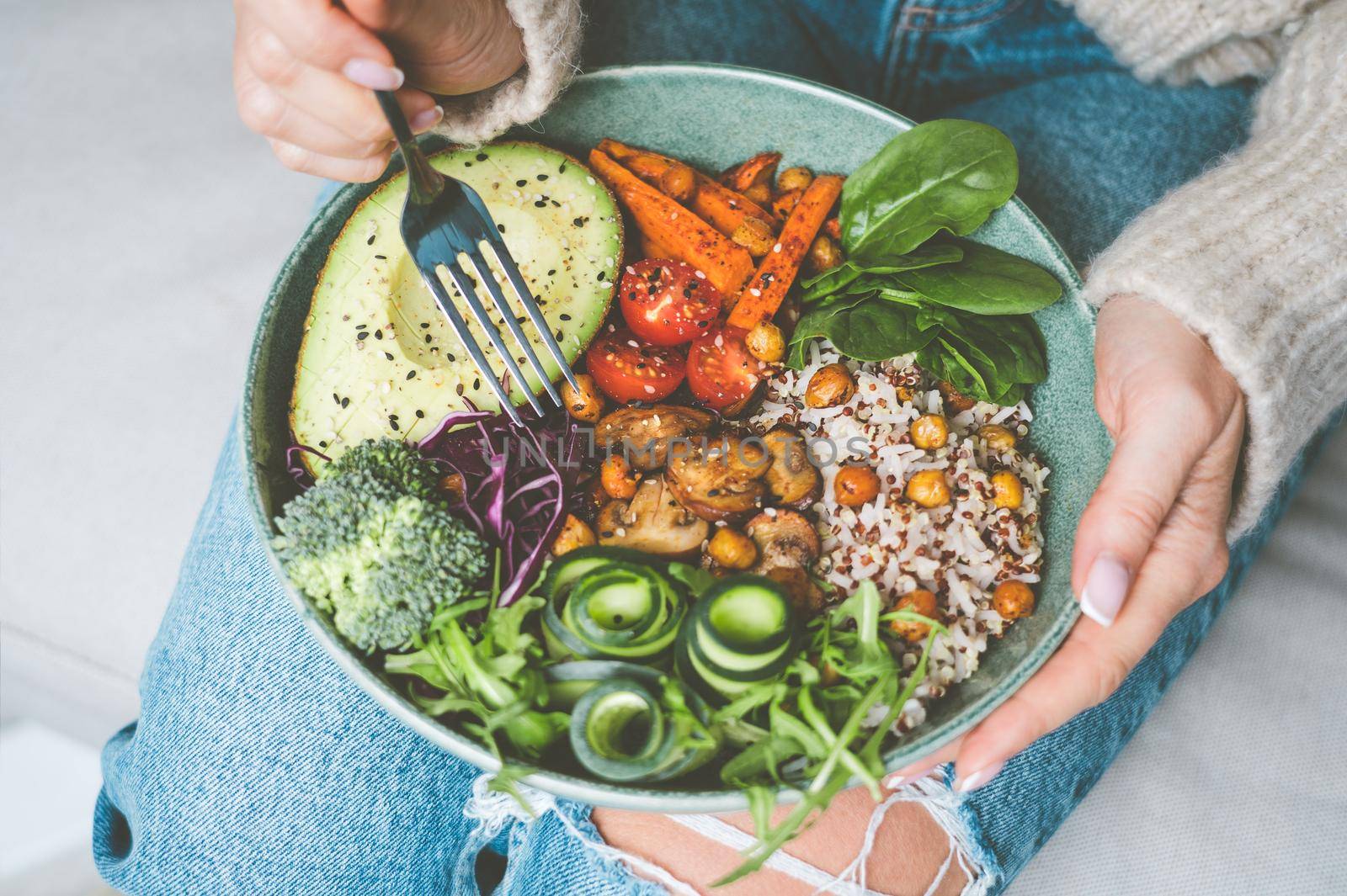 Woman eating healthy meal. Bowl with rice, quinoa, avocado, cucumber, broccoli and cucumber. Healthy diet, lunch or dinner. Healthy food plate by DariaKulkova