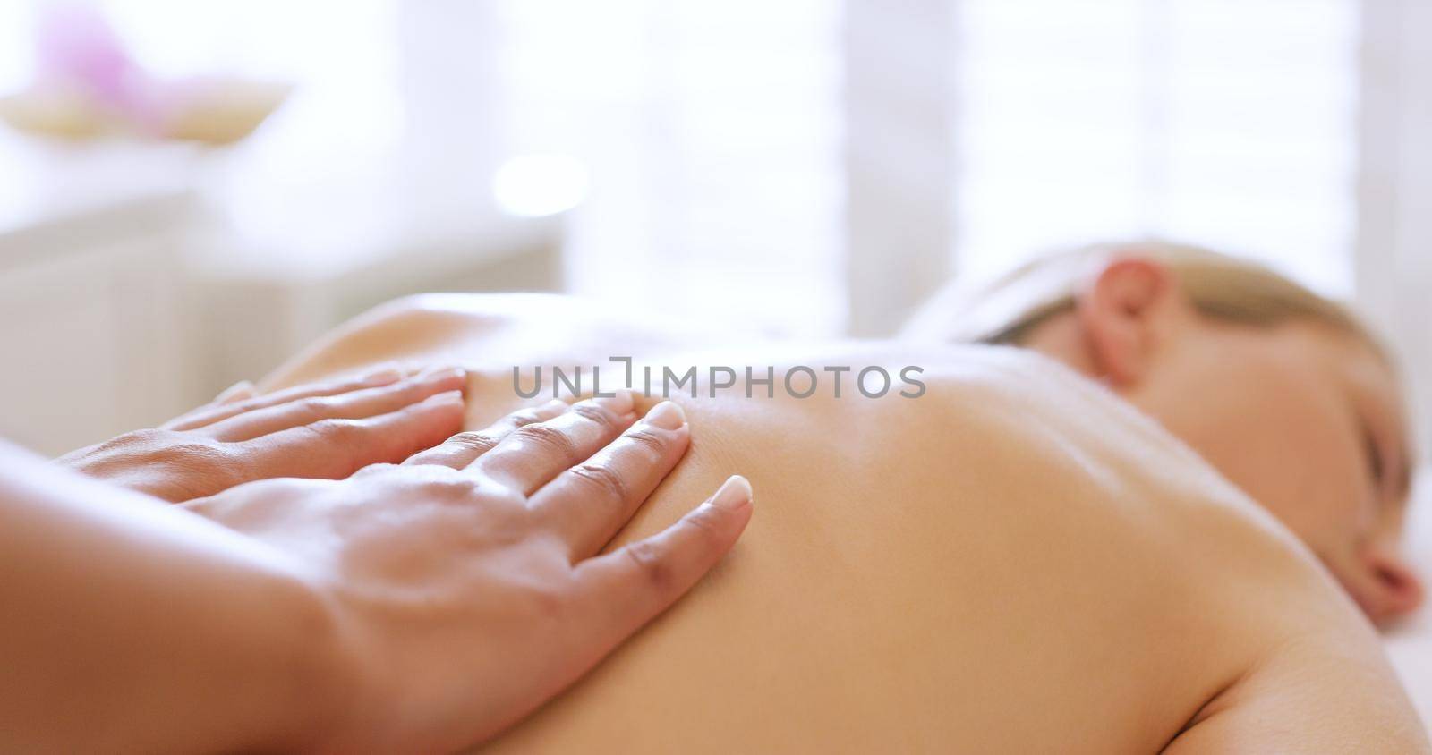 Shes got the midas touch. Shot of a beautiful young woman enjoying a back massage at a beauty spa. by YuriArcurs