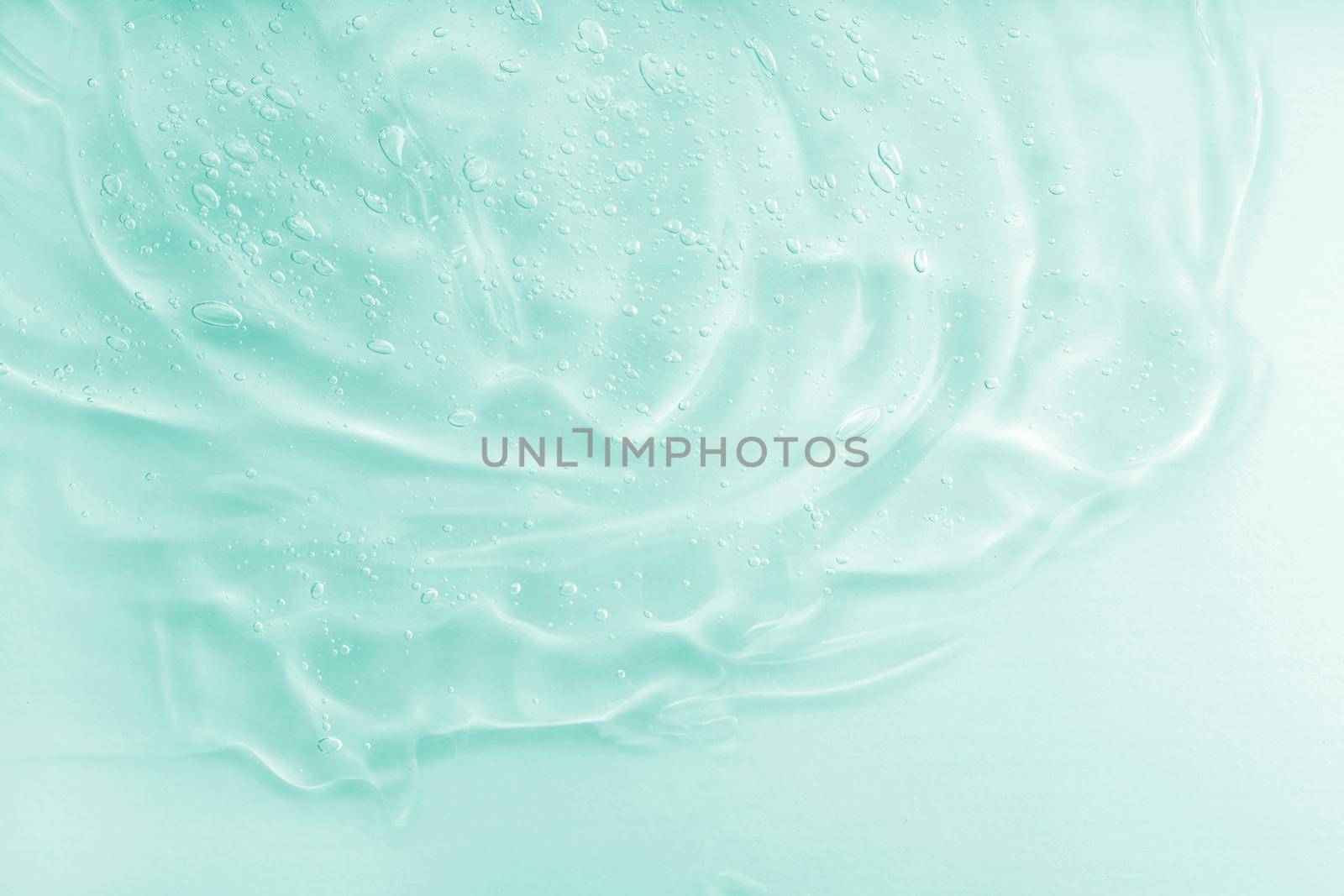 Liquid green oil smudge. The concept of natural cosmetics. Hyaluronic acid clear serum sample. Aloe vera cosmetic gel texture with bubbles background. Skincare moisturizing product. Close-up, macro.