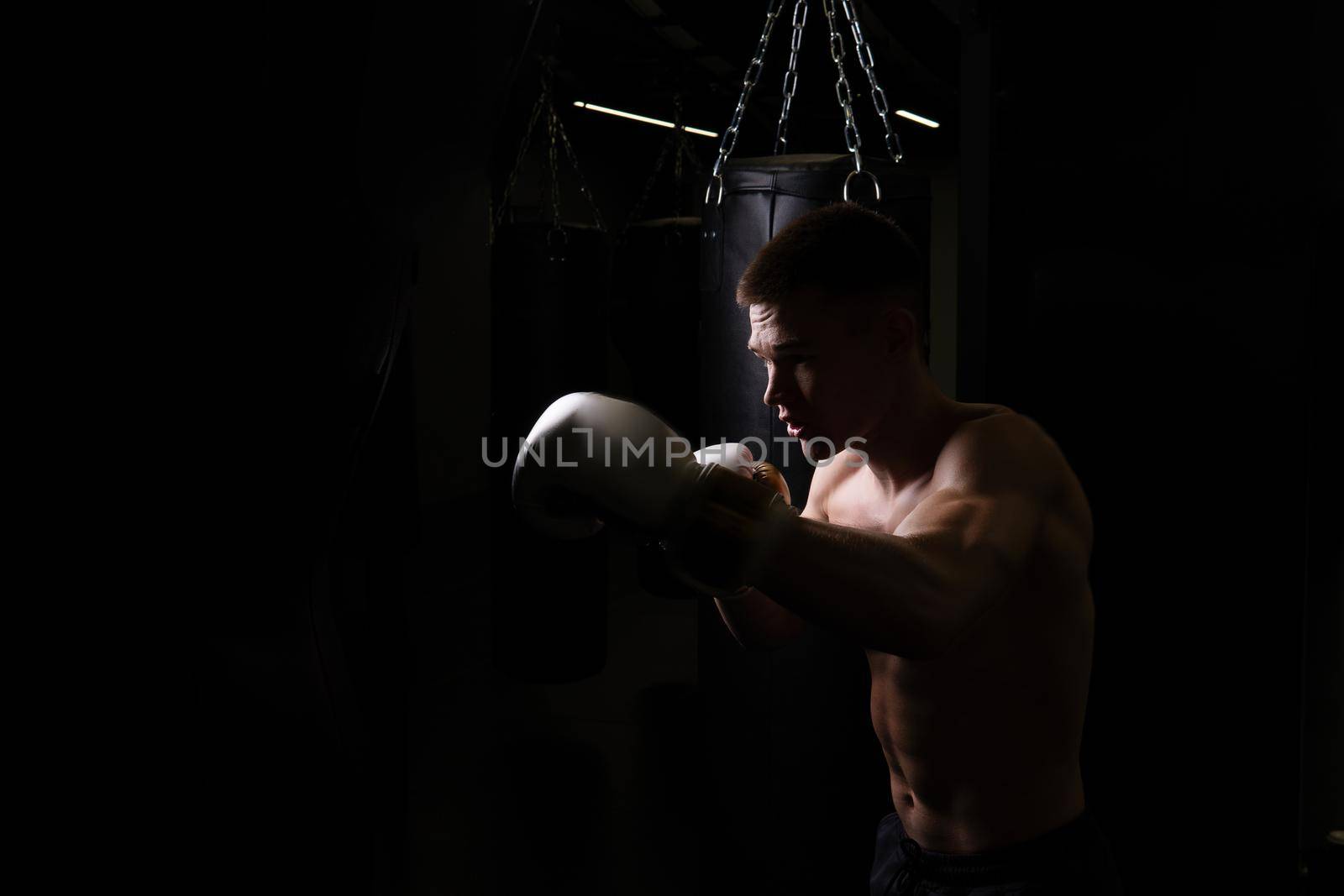 The blows the bag boxer practices athlete glove black young professional body, from strength fighter in combat for exercise lifestyle, training aggression. Backlit victory box, fitness