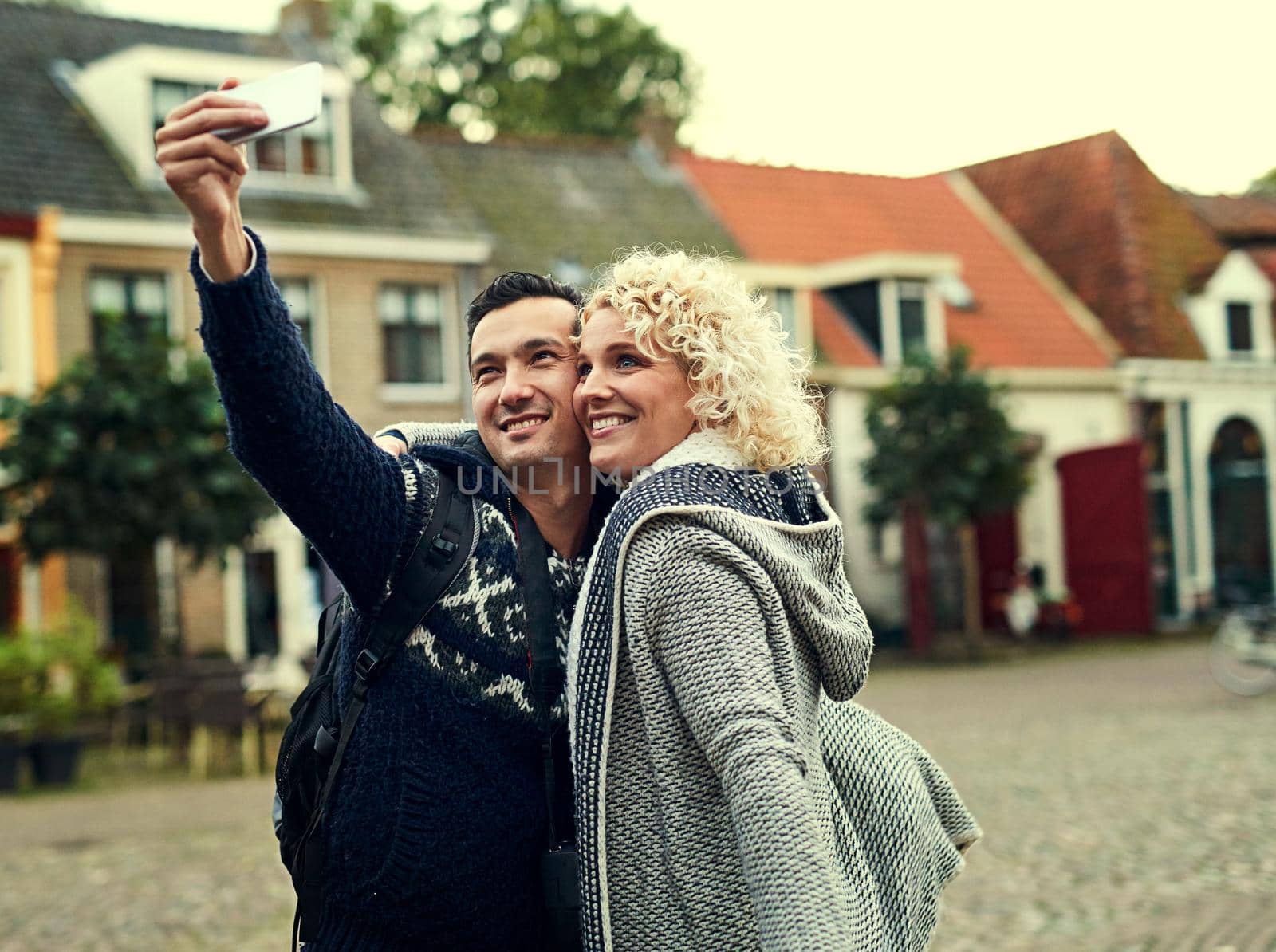 Taking a few selfies in a foreign city. Cropped shot of a young couple taking selfies while on vacation. by YuriArcurs