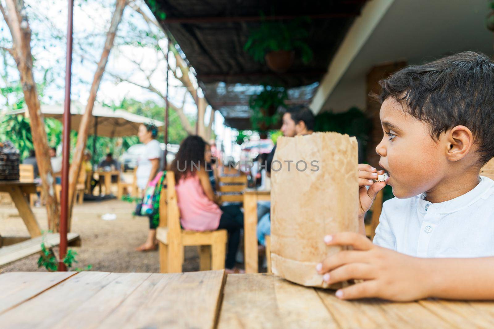 Latin boy eating popcorn in a restaurant for dessert by cfalvarez