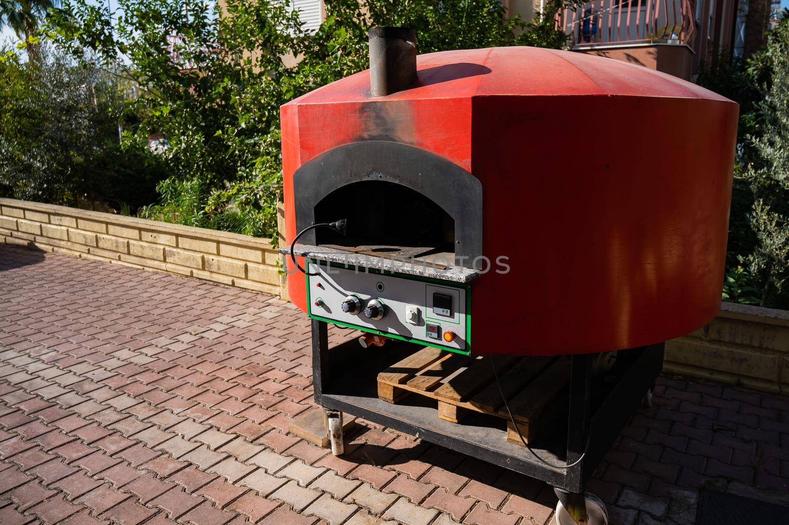 Large domed red metal outdoor pizza oven