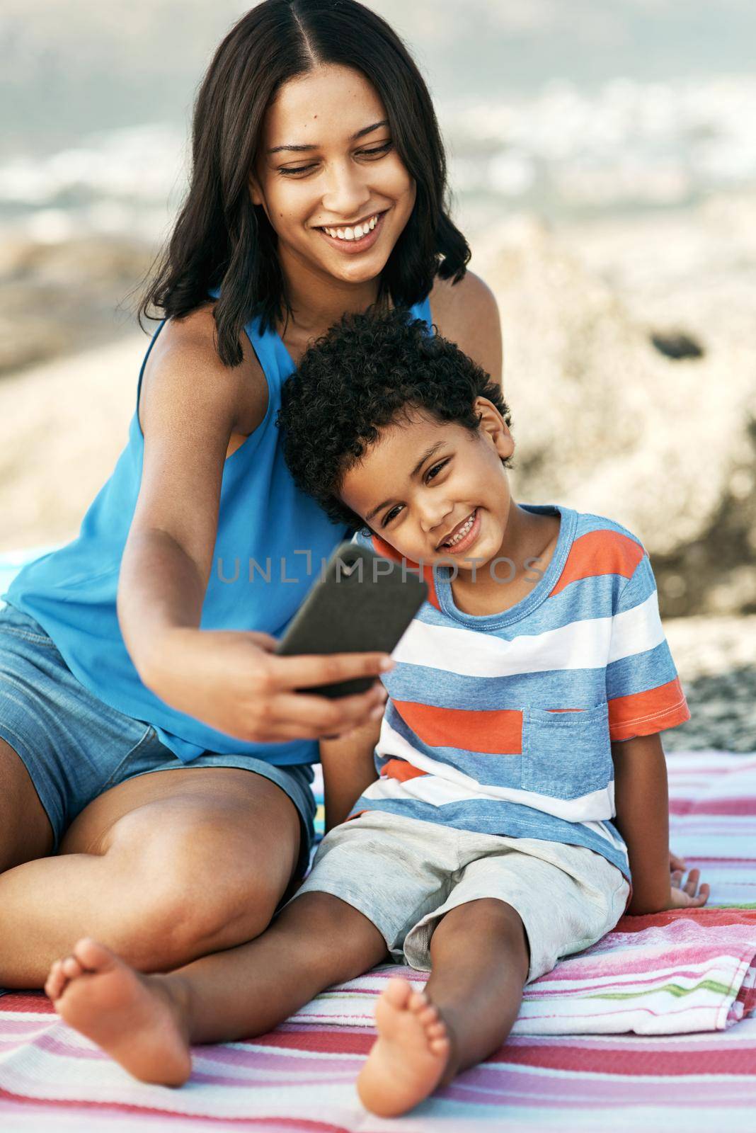 Shot of a mother and her son taking selfies at the beach.